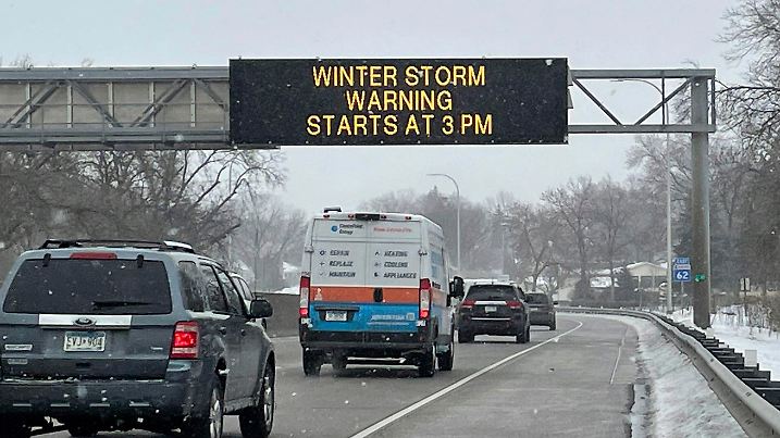 21.02.2023, USA, Minnesota: Fahrzeuge passieren ein Schild mit der Aufschrift "WINTER STORM WARNING STARTS AT 3PM" (Wintersturmwarnung beginnt um 15 Uhr) entlang des Interstate Highway 35 in der Nähe des internationalen Flughafens Minneapolis-Saint Paul. Weite Teile der USA bereiten sich auf einen schweren Wintersturm vor. In Kalifornien machte sich die Kaltfront bereits mit stark fallenden Temperaturen und stürmischen Winden bemerkbar. Foto: Trisha Ahmed/AP/dpa +++ dpa-Bildfunk +++