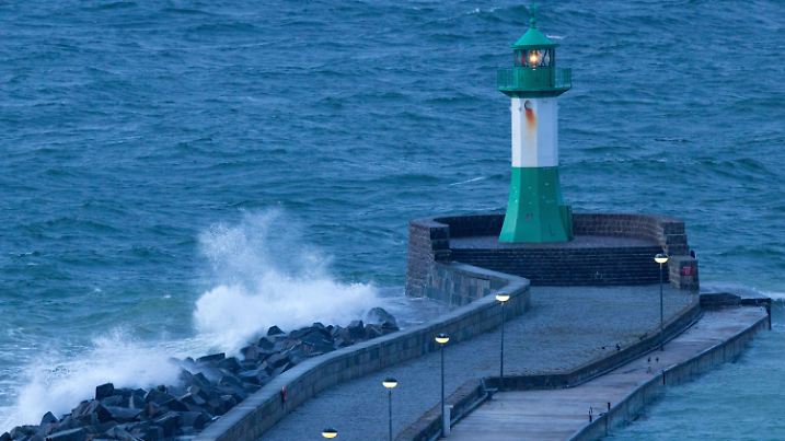 17.01.2023, Mecklenburg-Vorpommern, Sassnitz: Wellen brechen sich vor Sonnenaufgang an der Hafeneinfahrt an der Mole mit dem blinkenden Leuchtturm. Stürmisch und kühler zeigt sich das Winterwetter derzeit in Norddeutschland. Foto: Jens Büttner/dpa +++ dpa-Bildfunk +++