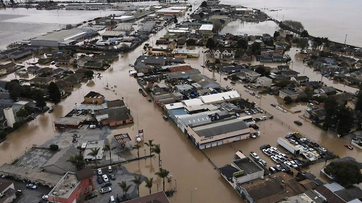 12.03.2023, USA, Pajaro: Dieses Luftbild zeigt den Großteil der Stadt Pajaro im Norden von Monterey County, die sich auf der anderen Seite des Pajaro River in der Nähe von Watsonville befindet. Die Behörden hatten daran gearbeitet, Teile des Deichsystems des Flusses zu stützen, als es gegen Mitternacht von Freitag auf Samstag durchbrochen wurde. Foto: Shmuel Thaler/The Santa Cruz Sentinel/AP/dpa - ACHTUNG: Nur zur redaktionellen Verwendung und nur mit vollständiger Nennung des vorstehenden Credits +++ dpa-Bildfunk +++