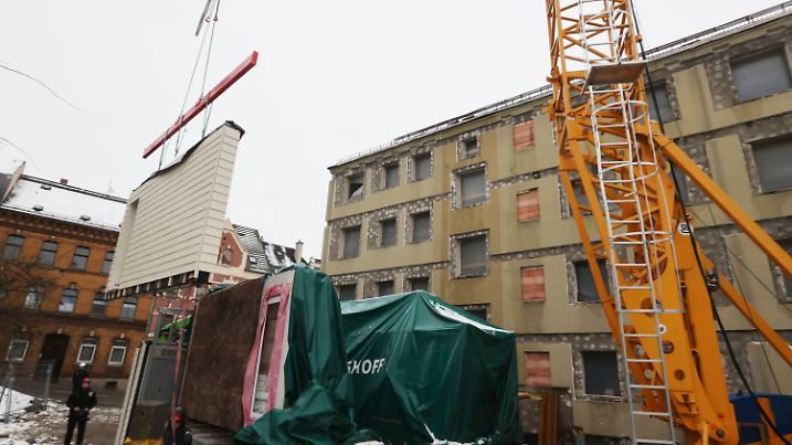 08.03.2023, Thüringen, Greiz: Energetisch ertüchtigte Fassadenmodule werden an einem Wohnblock montiert. Am Mittag fand die Übergabe des ersten seriell und klimaneutral sanierten Quartiers durch Thüringens Umweltminister statt. Gestiegene Bau- und Finanzierungskosten bedrohen insbesondere in Ostdeutschland zahlreiche Sanierungspläne. Mit der seriellen Sanierung ist dies zu wesentlich geringeren Kosten und in kürzerer Zeit möglich. Foto: Bodo Schackow/dpa +++ dpa-Bildfunk +++