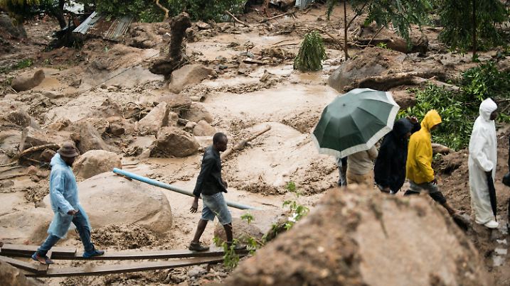 13.03.2023, Malawi, Blantyre: Menschen überqueren einen Fluss in Blantyre. Der außergewöhnlich langlebige Tropensturm «Freddy» hat zum zweiten Mal innerhalb eines Monats im Südosten Afrikas eine Spur der Verwüstung hinterlassen. In Malawi kamen mindestens 56 Menschen ums Leben, wie der staatliche Fernsehsender MBC mitteilte. Foto: Thoko Chikondi/AP +++ dpa-Bildfunk +++