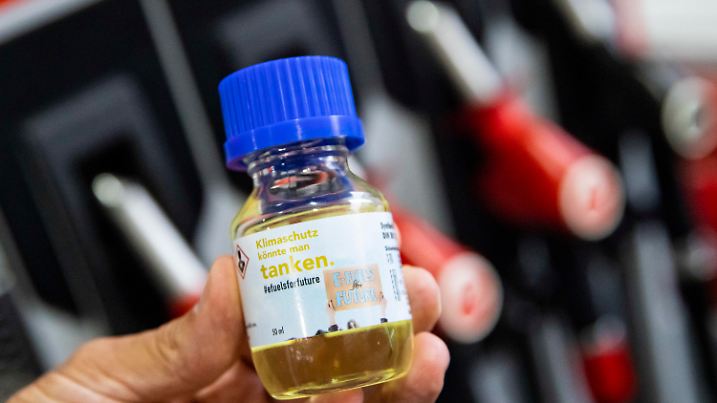 ARCHIV - 20.09.2021, Baden-Württemberg, Stuttgart: Eine Flasche mit der Aufschrift «Klimaschutz könnte man Tanken - E-Fules for Future» wird vor einer Zapfsäule an einer Tankstelle während einer E-Fuels-Probefahrt im Rahmen der Stuttgarter Mobilitätswoche gehalten. (zu dpa «Paris: Festhalten an E-Fuels ist industriepolitisch gefährlich») Foto: Tom Weller/dpa +++ dpa-Bildfunk +++