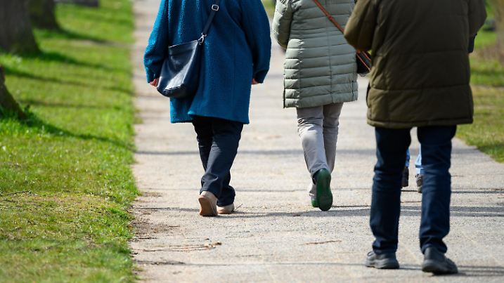 07.04.2023, Schleswig-Holstein, Lübeck: Spaziergänger laufen im Sonnenschein eine Allee entlang. Foto: Jonas Walzberg/dpa +++ dpa-Bildfunk +++