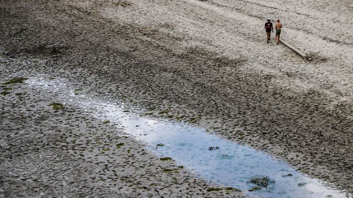 ARCHIV - 11.08.2022, Frankreich, Aiguines: Zwei Männer gehen bei Niedrigwasser über das schlammige Ufer am Stausee Lac de Sainte-Croix. Hitze und ausbleibende Niederschläge sorgten in ganz Frankreich im vergangenen Sommer für eine Dürre mit historischem Ausmaß. Nun trifft Frankreich angesichts anhaltender Trockenheit Sofortmaßnahmen, um sich für einen erneuten Dürre-Sommer zu rüsten. (zu dpa Frankreich trifft Sofortmaßnahmen wegen Wassermangels) Foto: Jan Woitas/dpa +++ dpa-Bildfunk +++