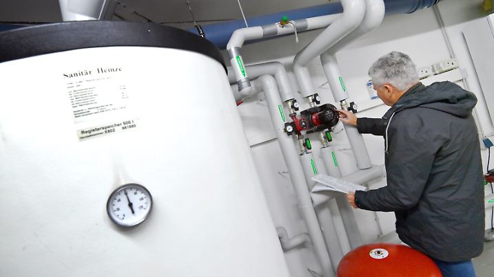 Themenfoto Gasheizung: Mann steht im Heizungskeller und nimmt Einstellungen an Umwaelzpumpen vor. ?