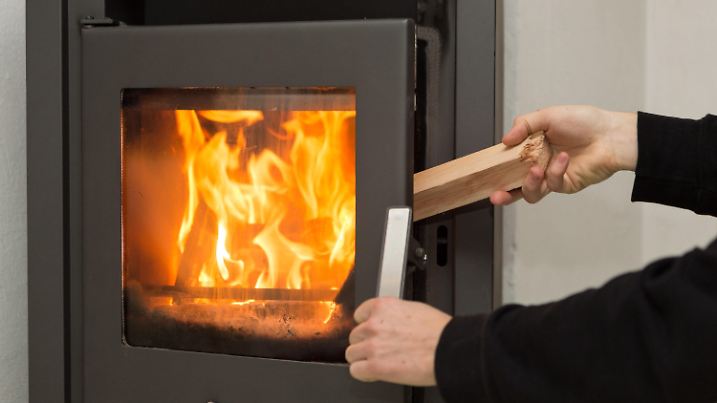 ARCHIV - 02.01.2017, Baden-Württemberg, Rottweil: Ein Mann legt in seiner Wohnung ein Stück Holz in einen Kaminofen, in dem ein Feuer brennt. Die Feinstaubimmissionen im Land bewegen sich nach Angaben der Landesanstalt für Umwelt Baden-Württemberg (LUBW) seit Weihnachten weiter auf einem niedrigen Niveau - auch dank des zu großen Teilen milden und wechselhaften Winters.  (zu dpa: «Kaum dicke Luft im Südwesten - Wie schädlich sind Holzöfen?») Foto: Silas Stein/dpa +++ dpa-Bildfunk +++