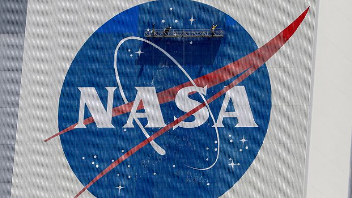 FILE PHOTO: Workers pressure wash the logo of NASA on the Vehicle Assembly Building before SpaceX will send two NASA astronauts to the International Space Station aboard its Falcon 9 rocket, at the Kennedy Space Center in Cape Canaveral, Florida, U.S., May 19, 2020. REUTERS/Joe Skipper/File Photo