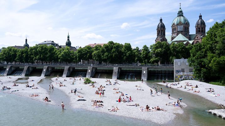 04.06.2023, Bayern, München: Zahlreiche Menschen genießen das schöne Wetter am Ufer der Isar in der Innenstadt. Im Hintergrund ist die Kirche St. Lukas zu sehen. Foto: Sven Hoppe/dpa +++ dpa-Bildfunk +++