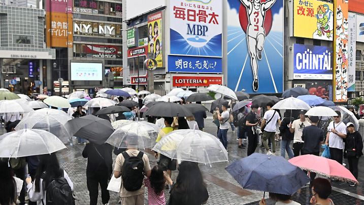 29.05.2023, Japan, Osaka: Fußgänger mit Regenschirmen gehen im Stadtteil Dotonbori durch den Regen. Foto: ---/kyodo/dpa +++ dpa-Bildfunk +++