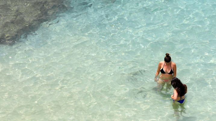 22.07.2023, Spanien, Calvia: Badegäste und Sonnenanbeter am Strand von Portals Nous auf Mallorca. Das Mittelmeer erwärmt sich einer Studie zufolge immer schneller und wird dabei auch immer salziger. Das Wasser erwärme sich infolge des Klimawandels mit einer Geschwindigkeit von etwa zwei Grad je 100 Jahre im westlichen Mittelmeer und an einigen Stellen sogar um drei Grad pro Jahrhundert, schrieben Wissenschaftler des spanischen Meeresforschungsinstituts ICM-CSIC in der Zeitschrift «Journal of Marine Science and Engineering». Foto: Clara Margais/dpa - ACHTUNG: Verwendung nur im vollen Format +++ dpa-Bildfunk +++