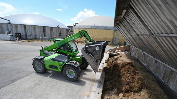 PRODUKTION - 03.07.2023, Baden-Württemberg, Hemmingen: Ein Mitarbeiter einer Biogasanlage von Naturenergie Glemstal befüllt die Anlage mit Biomasse. Der baden-württembergische Ministerpräsident Kretschmann stellt im Rahmen einer Pressekonfrenz die Biogasstrategie des Landes Baden-Württemberg vor. Foto: Bernd Weißbrod/dpa +++ dpa-Bildfunk +++