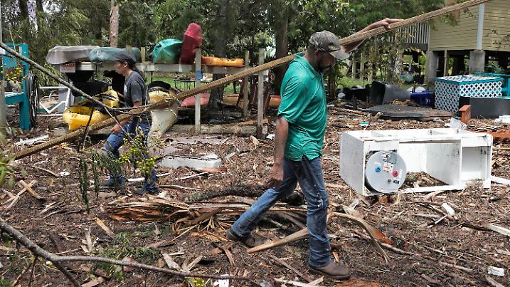 31.08.2023, USA, Zedernschlüssel: Lorena Torres (l) und Jorge Larancuent entfernen das Faraway Inn  von den Trümmern nach dem Hurrikan «Idalia». Foto: Chris O'Meara/AP +++ dpa-Bildfunk +++