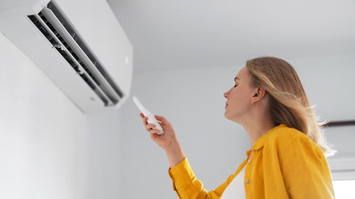 Women dying from the heat standing in front of the air conditioner.