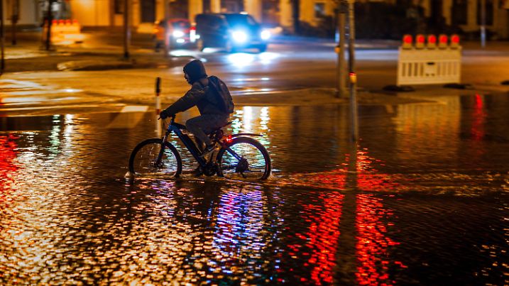 20.10.2023, Mecklenburg-Vorpommern, Wismar: Ein Radfahrer fährt durch das Hochwasser am Stadthafen. Wegen einer erwarteten Sturmflut an der Ostseeküste sind Uferbereiche in der Nähe des Hafens bereits teilweise überflutet. Das Bundesamt für Seeschifffahrt und Hydrographie erwartet in der Nacht zum 20.10.2023 mit teilweise einem Meter höheren Wasserständen. Wegen einer Sturmflutwarnung und steigender Wasserstände an der Ostsee sind die Küstenstädte in Mecklenburg-Vorpommern in erhöhter Wachbereitschaft. Foto: Jens Büttner/dpa +++ dpa-Bildfunk +++