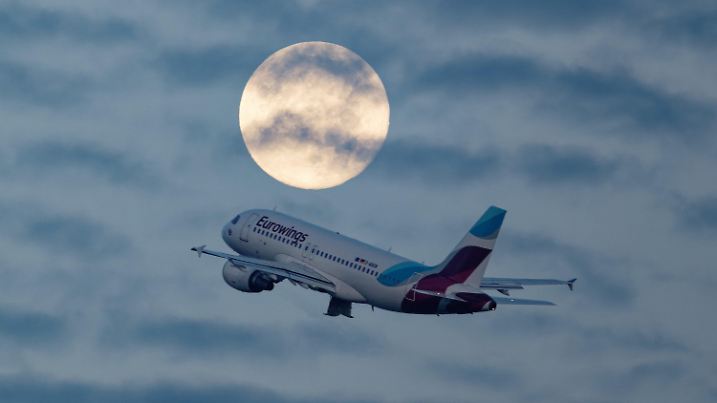 30.09.2023, Nordrhein-Westfalen, Düsseldorf: Ein Passagierflugzeug startet vom Flughafen in Düsseldorf, und passiert dabei den Vollmond. Foto: Henning Kaiser/dpa +++ dpa-Bildfunk +++