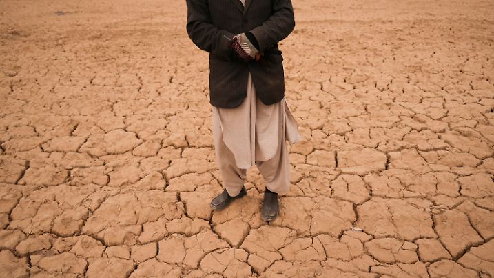ARCHIV - 13.12.2021, Afghanistan, Hachka: Abdul Haqim begutachtet sein karges Feld, auf dem er früher Weizen anbaute, um seine Familie zu ernähren. Eine schwere Dürre hat die ohnehin schon verzweifelte Lage in Afghanistan dramatisch verschlimmert. Der Boden auf diesem Feld ist total ausgetrocknet. Die Vereinten Nationen fürchten durch den Klimawandel eine Zunahme von Katastrophen mit schweren Auswirkungen auf Landwirtschaft und Ernährungssicherheit. Dies geht aus einem Bericht hervor, den die UN-Ernährungs- und Landwirtschaftsorganisation (FAO) am Donnerstag in Rom veröffentlichte. Foto: Mstyslav Chernov/AP/dpa +++ dpa-Bildfunk +++