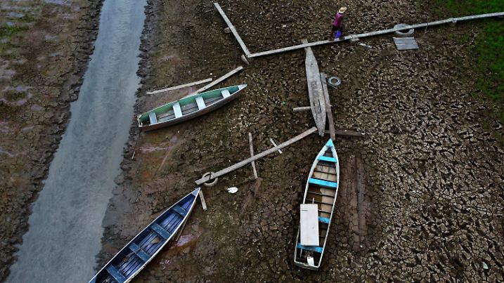 dpatopbilder - 21.10.2023, Brasilien, Manaquiri: Ein Anwohner geht neben Booten auf einem trockenen Abschnitt des Solimoes-Flusses in einer ländlichen Gegend des Staates Amazonas. Foto: Edmar Barros/AP +++ dpa-Bildfunk +++