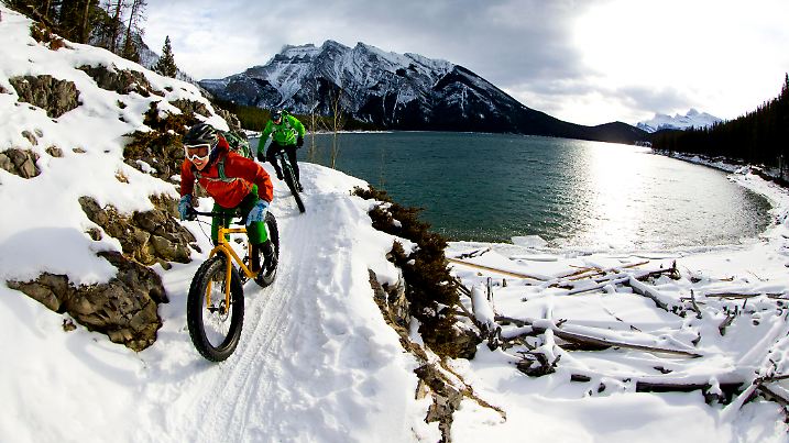 A woman and man enjoy a winter fat bike ride in Banff National Park, Alberta, Canada.