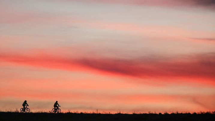 29.10.2023, Baden-Württemberg, Unlingen: Zwei Radfahrer sind am Morgen kurz vor Sonnenaufgang unterwegs. Foto: Thomas Warnack/dpa +++ dpa-Bildfunk +++