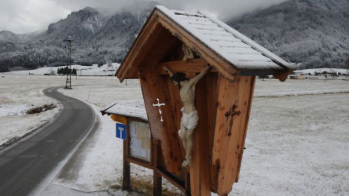 Schnee liegt am 24.01.2014 auf dem Dach eines Kruzifixes und auf den Feldern bei Eschenlohe (Landkreis Garmisch-Partenkirchen). Foto: Andreas Gebert/dpa +++(c) dpa - Bildfunk+++