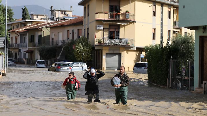 dpatopbilder - 03.11.2023, Italien, Toskana: Menschen gehen im Hochwasser über eine überschwemmte Straße. Schwere Unwetter mit heftigen Regenfällen haben die mittelitalienische Region Toskana in der Nacht zum Freitag heimgesucht. Foto: Str/Xinhua/dpa +++ dpa-Bildfunk +++
