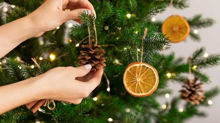 Female hands hanging handmade decoration on Christmas tree. Sustainable Christmas, zero waste, eco friendly.