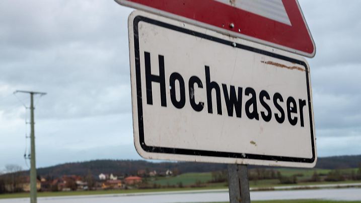 10.12.2023, Bayern, Hemmendorf: "Hochwasser" steht auf einem Achtungsschild. Nach Regen und Schneeschmelze erreicht das Hochwasser erste Straßen und Wohnbebauungen. Der Pegel Schenkenau / Itz ereicht nach Angaben des Hochwassernachrichtendienst (HND) Meldestufe 3. Foto: Pia Bayer/dpa +++ dpa-Bildfunk +++