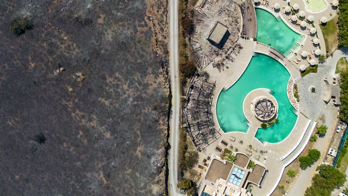 ARCHIV - 26.07.2023, Griechenland, Kiotari: Im Ort Kiotari ist das Feuer in den vergangenen Tagen bis an die Hotels am Strand vorgedrungen. Im Südosten der Ferieninsel Rhodos kämpfen die Menschen gegen die Flammen. (Luftaufnahme mit einer Drohne) (zu dpa: «Extremwetter-Jahr: Von Wassermassen, Waldbränden und Wirbelstürmen») Foto: Christoph Reichwein/dpa +++ dpa-Bildfunk +++