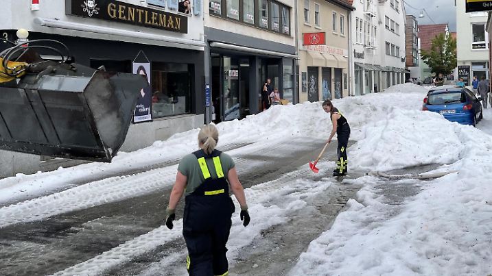 ARCHIV - 04.08.2023, Baden-Württemberg, Reutlingen: Einsatzkräfte der Feuerwehr räumen Hagel von einer Straße. Winterdienst-Einsatz mitten im Sommer: Ein lokal begrenztes Unwetter hat Straßen in der Innenstadt von Reutlingen mit einer hohen Hagel-Schicht überzogen. Foto: Schulz/SDMG/dpa +++ dpa-Bildfunk +++