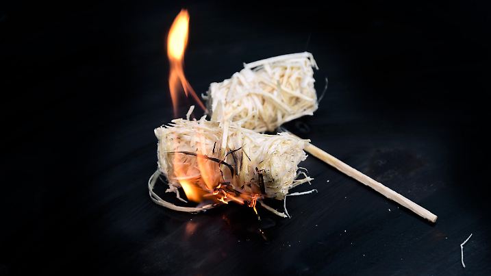 burning wood wool barbecue lighter on a black metal bowl, copy space, selected focus