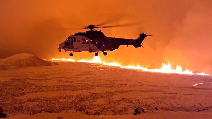HANDOUT - 19.12.2023, Island, Grindavik: Dieses Bild, das aus einem von der isländischen Küstenwache zur Verfügung gestellten Video stammt, zeigt ihren Hubschrauber, der in der Nähe von Magma fliegt, das auf einem Hügel in der Nähe von Grindavik auf der isländischen Halbinsel Reykjanes fließt, am späten 18.12.2023 oder frühen 19.12.2023. Nach einer wochenlangen Erdbebenserie hat es auf der Reykjanes-Halbinsel in Island am späten Montagabend einen vulkanischen Ausbruch gegeben. Foto: Uncredited/Icelandic Coast Guard/AP/dpa - ACHTUNG: Nur zur redaktionellen Verwendung und nur mit vollständiger Nennung des vorstehenden Credits +++ dpa-Bildfunk +++