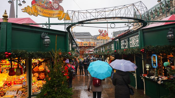 27.11.2023, Hamburg: Besucherinnen und Besucher mit Regenschirmen gehen bei der Eröffnung des Hamburger Weihnachtsmarkts auf dem Rathausmarkt zwischen den Marktbuden. In Hamburg starten am Montag die meisten der Weihnachtsmärkte. Foto: Christian Charisius/dpa - ACHTUNG: Verwendung nur im vollen Format +++ dpa-Bildfunk +++