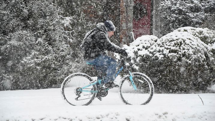 07.01.2024, USA, North Adams: Ein Radfahrer fährt auf dem Bürgersteig der State Road während eines heftigen Schneesturms. Foto: Gillian Jones-Heck/The Berkshire Eagle/AP/dpa - ACHTUNG: Nur zur redaktionellen Verwendung und nur mit vollständiger Nennung des vorstehenden Credits +++ dpa-Bildfunk +++