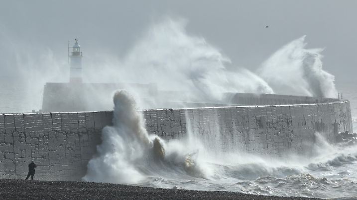 A person views as large waves hit the harbour wall at sunrinse during Storm Isha in Newhaven, southern Britain, January 22, 2024. REUTERS/Toby Melville