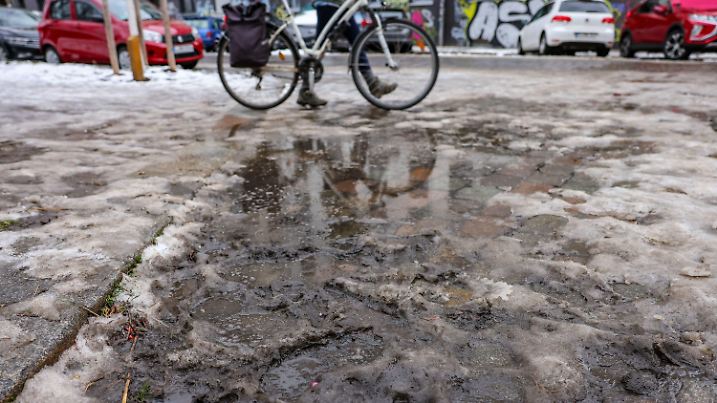 22.01.2024, Sachsen, Leipzig: Eine Frau schiebt ihr Fahrrad durch den Schneematsch. In der Nacht stiegen die Temperaturen in die Plusgrade und es setzte Tauwetter ein. Nach dem vielerorts sonnigen Winterwochenende stellt sich die Wetterlage der Vorhersage nach wieder um - es werden feuchtes Tauwetter und teilweise schwere Sturmböen erwartet. Foto: Jan Woitas/dpa +++ dpa-Bildfunk +++