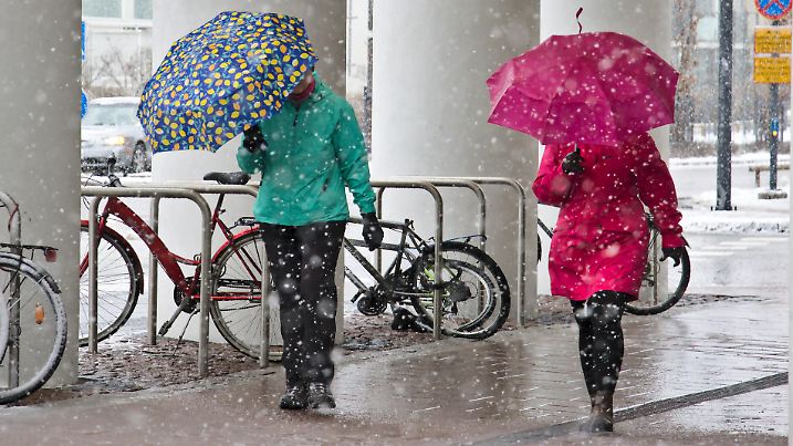Espoo, Finland – April 16, 2020: Pedestrians equipped with umbrellas. Spring day has turned to snowfall. Finland.