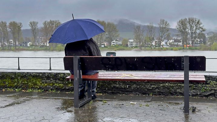 Wetter, Regen, Person unterm Schirm auf einer Bank sitzend, am Rheinufer in Bonn Bad Godesberg, Regenwetter, Aprilwetter, April, Symbolbild, Symbolfoto, am 01.04.2024 *** Weather, rain, person sitting under an umbrella on a bench, on the banks of the Rhine in Bonn Bad Godesberg, rainy weather, April weather, April, symbolic picture, symbol photo, on 01 04 2024
