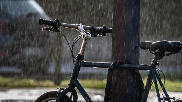 ARCHIV - 26.02.2020, Hessen, Frankfurt/Main: Ein an einer Laterne festgeschlossenes Fahrrad wird von der Sonne angeleuchtet, während gleichzeitig ein kurzer Regenschauer niedergeht. (zu dpa: «Schauer und Abkühlung in Hessen erwartet») Foto: Frank Rumpenhorst/dpa +++ dpa-Bildfunk +++