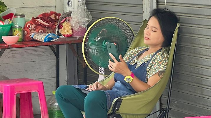 01.05.2024, Thailand, Bangkok: Eine Frau sitzt in Bangkok vor einem Ventilator, um sich abzukühlen. Eine extreme Hitzewelle hat Thailand und andere Länder Asiens seit Wochen fest im Griff. Der Hitzeindex, also die gefühlte Temperatur, liegt teilweise bei über 50 Grad Celsius. (zu dpa: «Wie im Backofen: Rekord-Hitzewelle von Thailand bis Vietnam») Foto: Carola Frentzen/dpa +++ dpa-Bildfunk +++