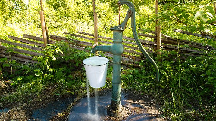 Old retro hand water pump outside in the garden