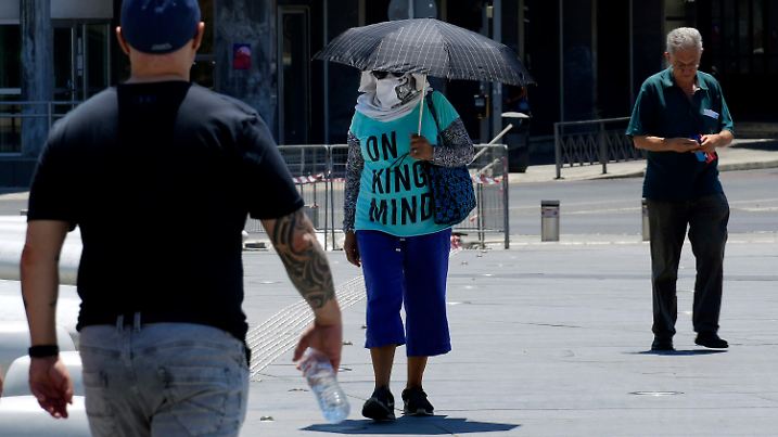 04.06.2024, Zypern, Nikosia: Eine Frau schützt sich an einem heißen Tag mit einem Regenschirm und einem Schal auf dem Elephtherias-Platz im Zentrum der Hauptstadt vor der Sonne. Das Meteorologische Amt teilte mit, dass die Höchsttemperaturen der Hitzewelle in diesen Tagen im Landesinneren 42 Grad Celsius und im Troodos-Gebirge 32 Grad Celsius erreichen sollen. Foto: Petros Karadjias/AP +++ dpa-Bildfunk +++