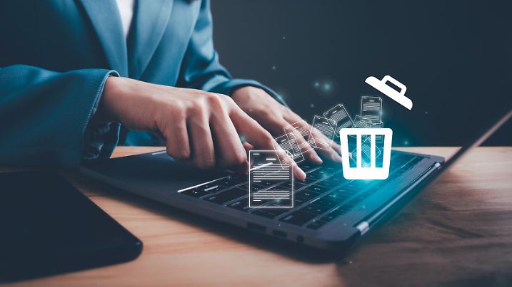 Businesswoman using computer laptop or smartphone delete files from a computer or from the Internet. Concept of deleting files, contacts, putting in order, cleaning service, trash can and files.