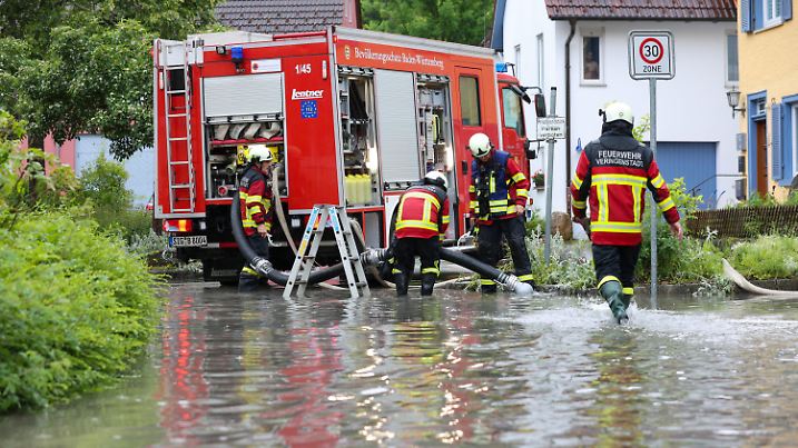 08.06.2024, Baden-Württemberg, Veringenstadt: Einsatzkräfte der Feuerwehr im Einsatz nach einem Unwetter mit Starkregen auf einer überfuteten Straße. Foto: Thomas Warnack/dpa +++ dpa-Bildfunk +++
