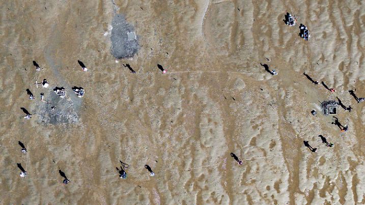 PRODUKTION - 15.05.2024, Schleswig-Holstein, Nordstrand: Forschende des Archäologischen Landesamtes, des Zentrums für Baltische und Skandinavische Archäologie sowie der Kieler und der Mainzer Universität stehen an einer Ausgrabungsstelle im Watt. Ein Team erfasste bei der Hallig Südfall durch geophysikalische Arbeiten eine bislang unbekannte, zwei Kilometer lange Kette mittelalterlicher Warften des untergegangenen Handelsplatzes Rungholt im nordfriesischen Wattenmeer. Eine dieser Warften zeige Strukturen, die zweifelsfrei als Fundamente der Rungholter Kirche von 40 mal 15 Meter Größe zu deuten seien. Der Handelsplatz Rungholt fiel 1362 einer verheerenden Sturmflut zum Opfer, der «Groten Mandränke». Sie gilt als Geburtsstunde Nordfrieslands in seiner heutigen Form. Sie trennte Halbinseln vom Festland und verpasste der damaligen Insel Strand einen Keil. (zu dpa: «Suche nach sagenumwobenem Rungholt an der Nordsee») Foto: Frank Molter/dpa +++ dpa-Bildfunk +++