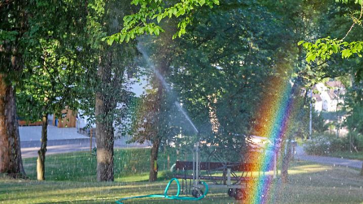 Traumhaftes Sommerwetter. Es wird ein heisser Tag im Siegerland. Wiesen und Baeume werden am fruehen Morgen im Schlosspark am Oberen Schloss bewaessert. Im Vordergrund ein Regenbogen. Sommer im Siegerland am 19.07.2022 in Siegen/Deutschland. *** Dreamlike summer weather It becomes a hot day in the Siegerland Meadows and trees are watered in the early morning in the castle park at the upper castle In the foreground a rainbow Summer in the Siegerland on 19 07 2022 in Siegen Germany