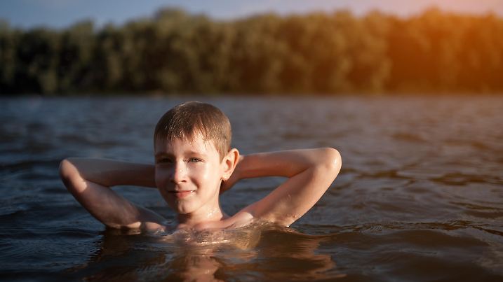 cheerful small boy have fun on the beach in rays of sun;