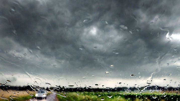 ARCHIV - 27.07.2013, Nordrhein-Westfalen, Düsseldorf: Regen läuft eine Windschutzscheibe hinunter. Am Himmel ziehen dunkle Wolken auf. (zu dpa: «Gewitter und Regen in Nordrhein-Westfalen») Foto: Martin Gerten/dpa +++ dpa-Bildfunk +++