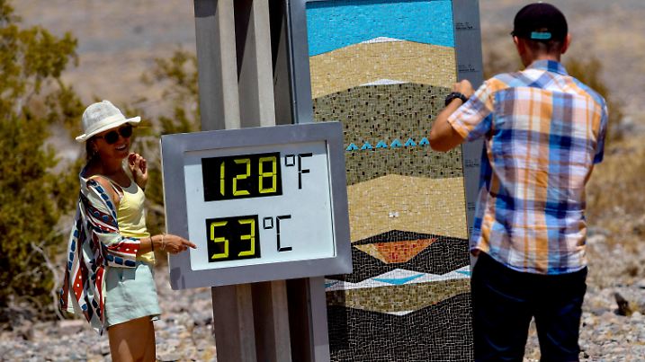 09.07.2024, USA, Death Valley: Touristen fotografieren ein Thermometer im Furnace Creek Visitor Center während einer Hitzewelle im Death Valley. Das Thermostat ist ungenau und zeigt die Temperatur um 1 bis 5 Grad Fahrenheit höher an als präzisere Instrumente, was für Fotos einen eindrucksvolleren Wert ergibt. Foto: Ty ONeil/AP +++ dpa-Bildfunk +++