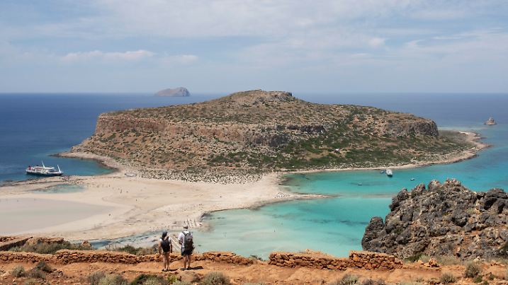 ARCHIV - 12.05.2022, Griechenland, Kissamos: Touristen gehen mit Blick auf den Strand von Balos und seine Lagune im nordöstlichen Teil der Insel Kreta entlang. (zu dpa: «Deutscher Wanderer auf Kreta ums Leben gekommen») Foto: Socrates Baltagiannis/dpa +++ dpa-Bildfunk +++
