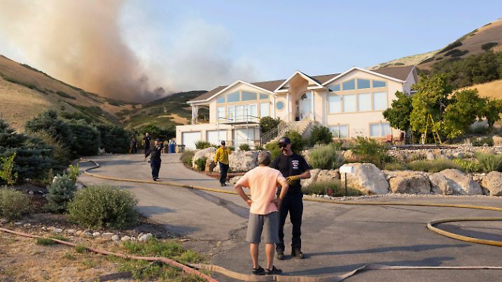 A Salt Lake City firefighter tells a local resident to evacuate as a wildfire around Ensign Peak grows closer to his home on Twickenham Drive in Salt Lake City on Saturday, July 20, 2024. (Brice Tucker/The Deseret News via AP)
